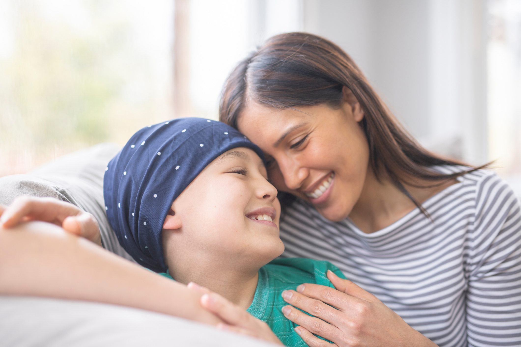 Portrait of a young boy battling cancer as his mom embraces him